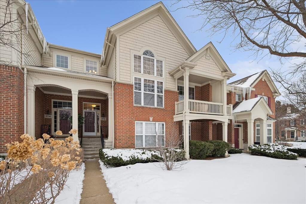 Brick townhouse with snow-covered front yard.