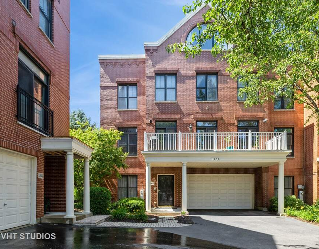 Brick townhouse with garage and balcony.