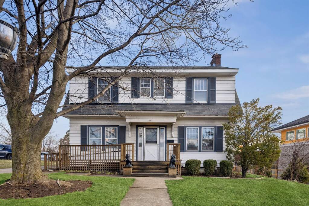 Two-story house with front porch and trees.
