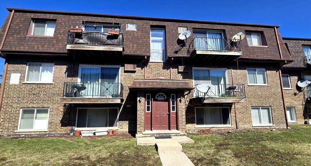 Three-story brick apartment building, sunny day.