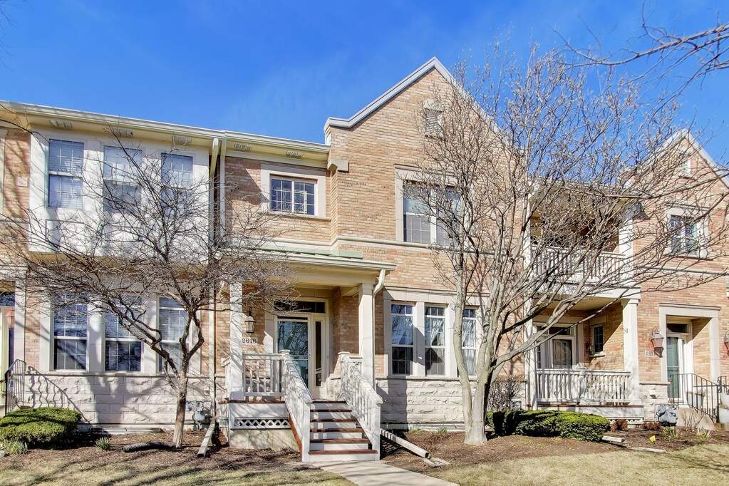 Brick townhouse with front steps and trees.