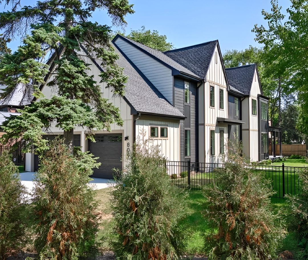 Modern suburban house with trees and fence.